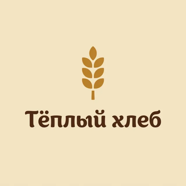 Logo der Bäckerei „Tjoply Chleb“ („Warmes Brot“): eine Ähre über dem kyrillischen Schriftzug, Braun und Karamell auf cremefarbenem Hintergrund
